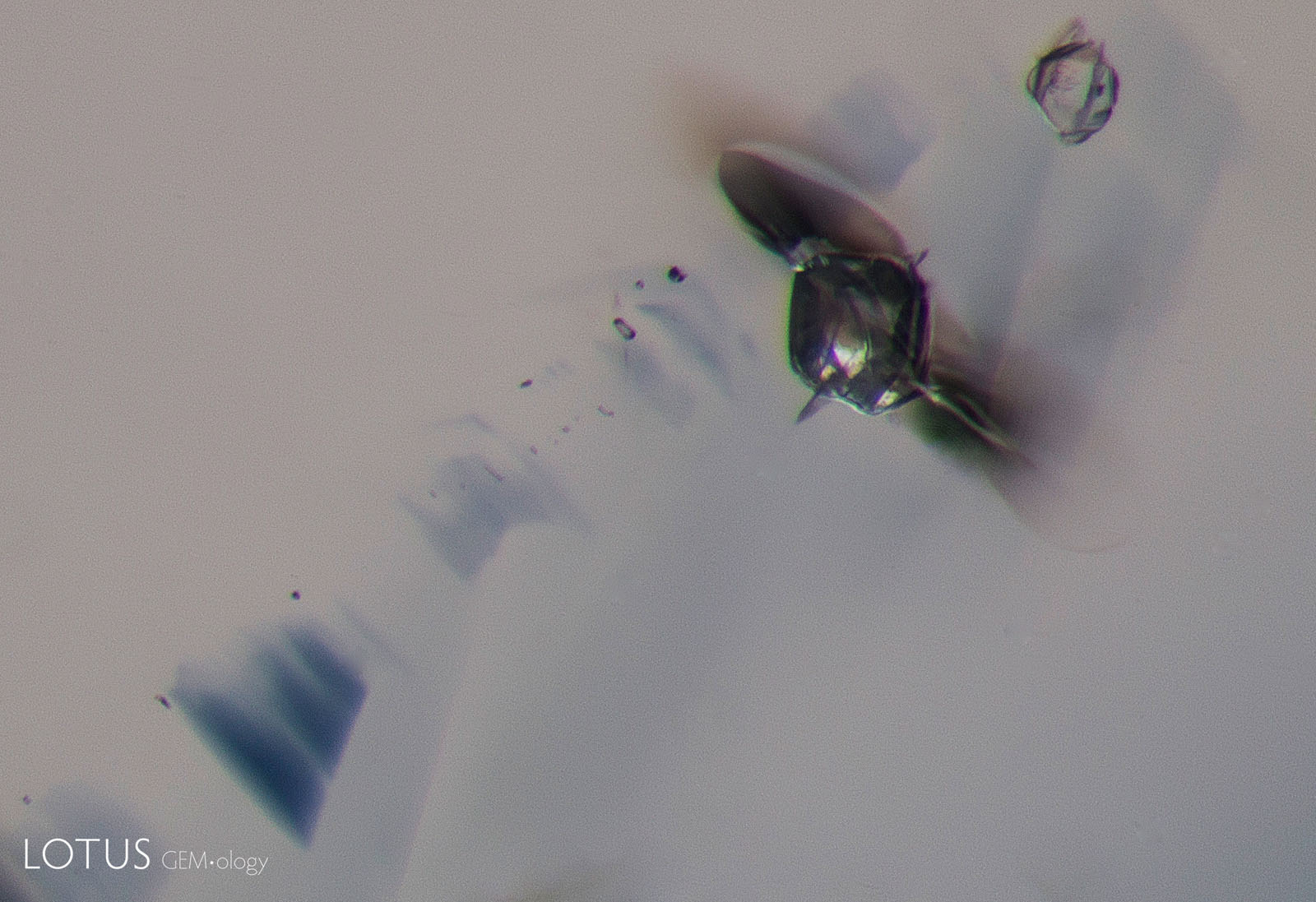 C: At 1100°C, the fissure has become larger, and a tiny fissure has begun to develop around the smaller crystal.