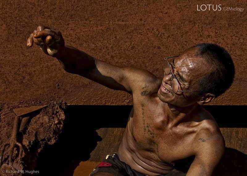 One of the last remaining sapphire miners at Khao Ploi Waen examines a find. Photo &copy; Richard W. Hughes.