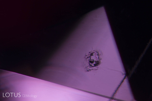A melted crystal of what was probably mica with a trapped gas bubble reveals this Mozambique ruby has been subjected to heat treatment.