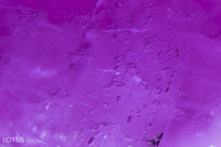 Flattened gas bubbles create irregular shapes in a fissure in a glass hybrid ruby.