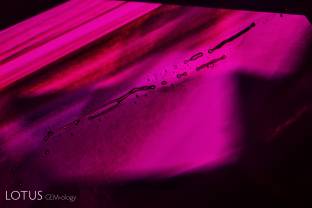 During flux healing, as the process continues, contraction bubbles form and then become larger as the void becomes more spherical. The degree of healing in flux-healed Mong Hsu rubies is so great that the flux remnants are often quite rounded, complete with contraction bubbles. Imagine a synthetic corundum crystal that has a long, thin hot-dog shaped gas bubble in it. If we heat that crystal to a high temperature, the hot dog will break up into a row of spherical bubbles, a process known as “necking down.” This image vividly illustrates the necking down of a void in a flux-healed Mong Hsu ruby.