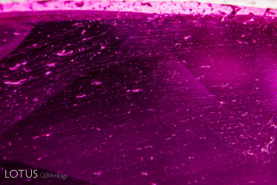 Douros synthetic flux ruby overgrowth on a natural seed. The overgrowth is quite thin and the interface shows tiny spots in lines.